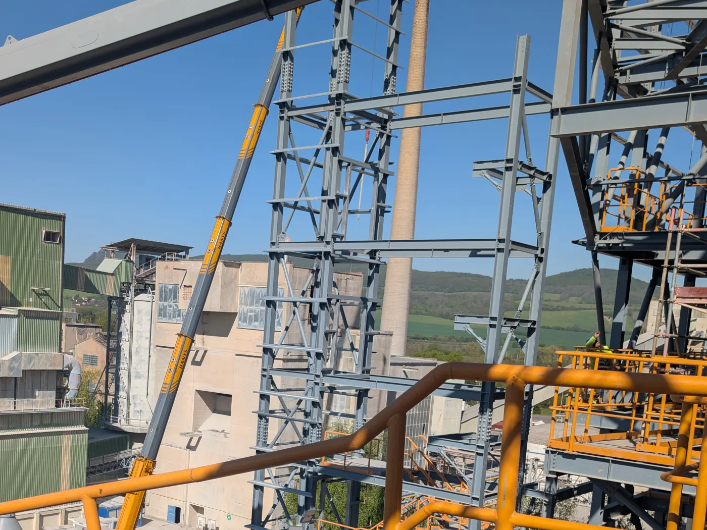 Lešení a ocelová konstrukce na průmyslové stavbě ohrazené výstražnou páskou