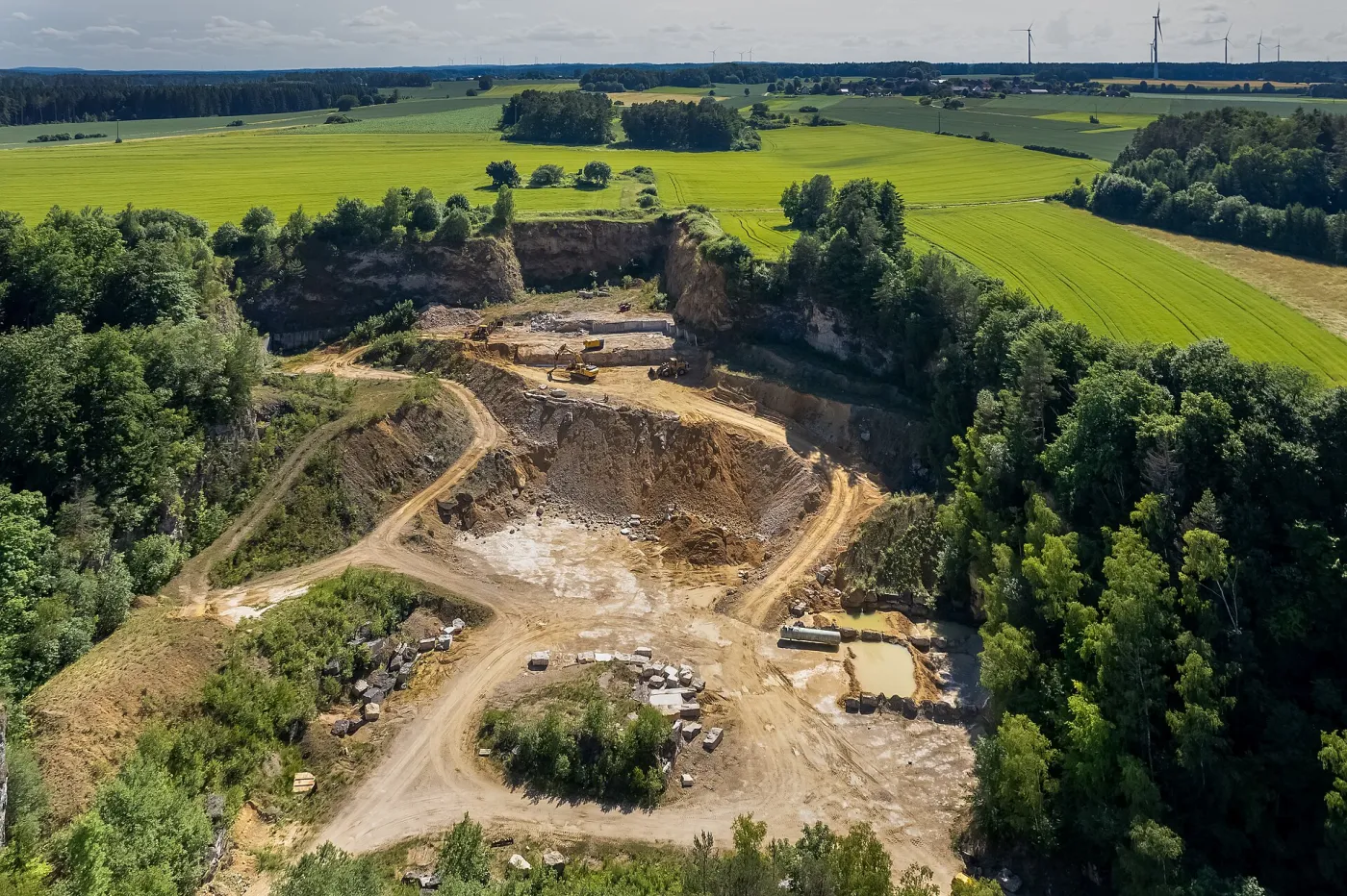 Letecký snímek lomu s etážemi, cestami a deponiemi mezi poli