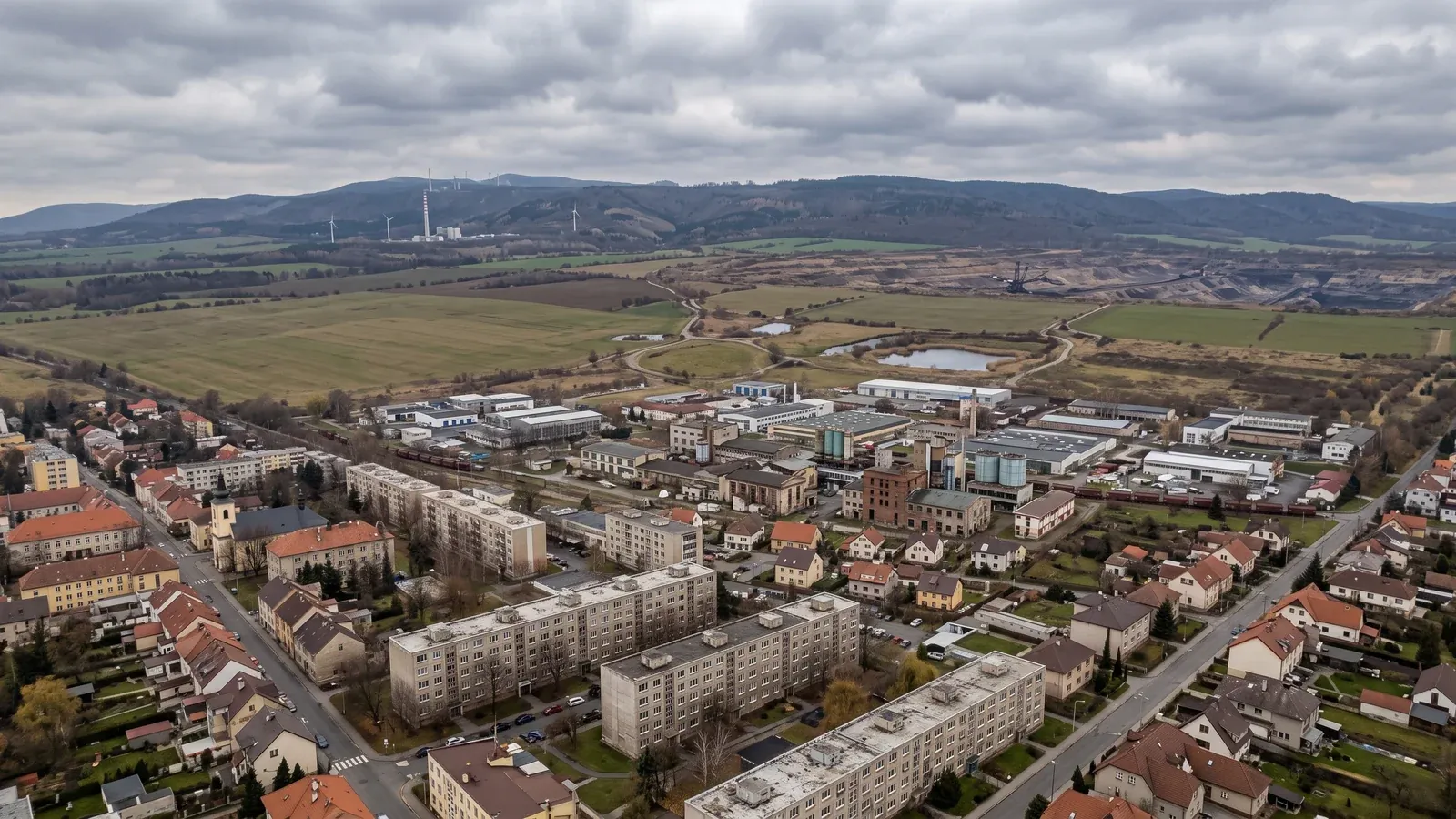 Zástavba Podkrušnohoří z výšky, panelové domy a rodinné domy pod hřebenem Krušných hor